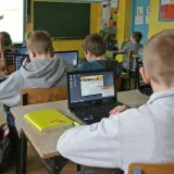 Dzieci w szkole pracują na laptopach. Nauczycielka tłumaczy materiał. Ile czasu ma nauczyciel na sprawdzenie sprawdzianu?