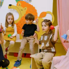 Nauczycielka i dzieci bawią się dzwonkami. Kto może prowadzić tus? Dzieci na zajęciach muzycznych.
