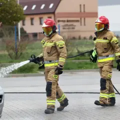 Strażak w pełnym rynsztunku PSP, z wężem wodnym, podczas akcji. Ciekawe, ile zarabia starszy aspirant w straży pożarnej za taką służbę.