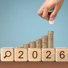 Klocki z napisem "2026" i lupą, na nich rosnące stosy monet. Czy to podpowiedź, ile zarabia nauczyciel mianowany w przedszkolu?
