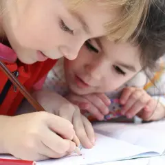 Dwie dziewczynki uczą się razem, by poprawić oceny. Prawo oświatowe wspiera takie wspólne nauczanie.