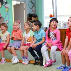 Uśmiechnięte dzieci siedzą w przedszkolu. Od ilu lat można tu chodzić?