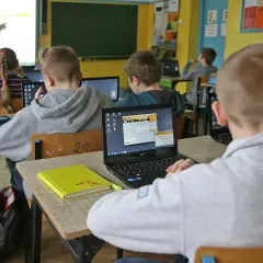 Dzieci w szkole pracują na laptopach. Nauczycielka tłumaczy materiał. Ile czasu ma nauczyciel na sprawdzenie sprawdzianu?