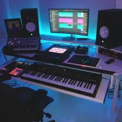 Nowoczesne studio muzyczne z syntezatorami, kontrolerami MIDI i komputerem, ukazujące zastosowanie komputerów w muzyce.