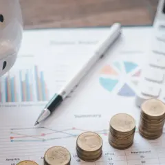 Świnka-skarbonka, monety, kalkulator i kompas na wykresach. Planowanie przyszłości po studiach finanse i rachunkowość.
