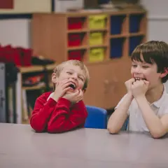Dwóch chłopców śmieje się wesoło w klasie. Ich oceny z zachowania w szkole z pewnością będą wysokie!