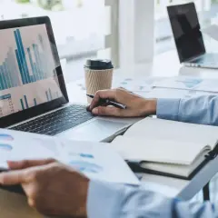 Praca z danymi i wykresami na laptopie, analiza raportów. To właśnie może być co po studiach ekonomicznych.