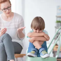 Nauczycielka wspomagająca rozmawia z chłopcem, który wygląda na smutnego. Jej pensum obejmuje wsparcie dzieci w trudnych chwilach.