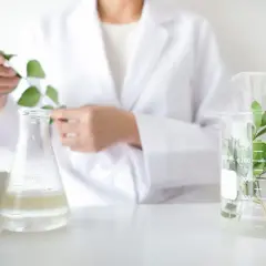 Biolog w białym fartuchu bada rośliny w laboratorium. Zastanawiasz się, ile zarabia biolog?