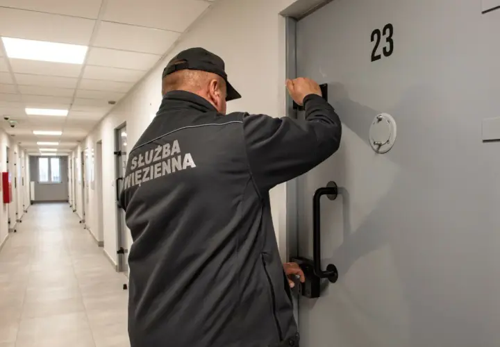 Wychowawca w więzieniu przy drzwiach celi nr 23. Zastanawiasz się, ile zarabia wychowawca w więzieniu?