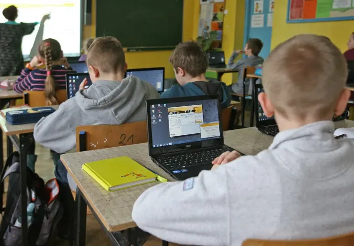 Dzieci w szkole pracują na laptopach. Nauczycielka tłumaczy materiał. Ile czasu ma nauczyciel na sprawdzenie sprawdzianu?