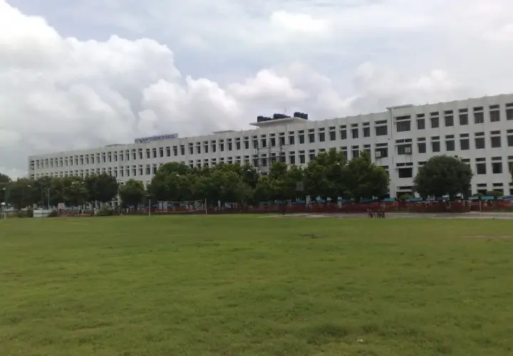 Ogromny budynek City Montessori School, być może największa szkoła na świecie, z zielonym boiskiem przed nim.
