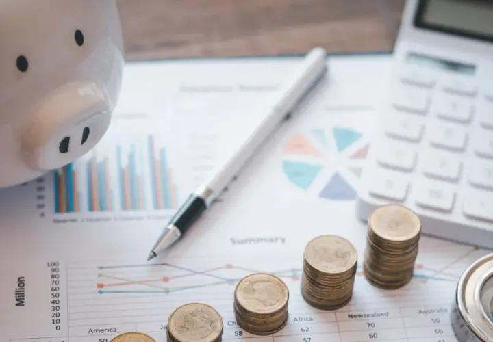 Świnka-skarbonka, monety, kalkulator i kompas na wykresach. Planowanie przyszłości po studiach finanse i rachunkowość.