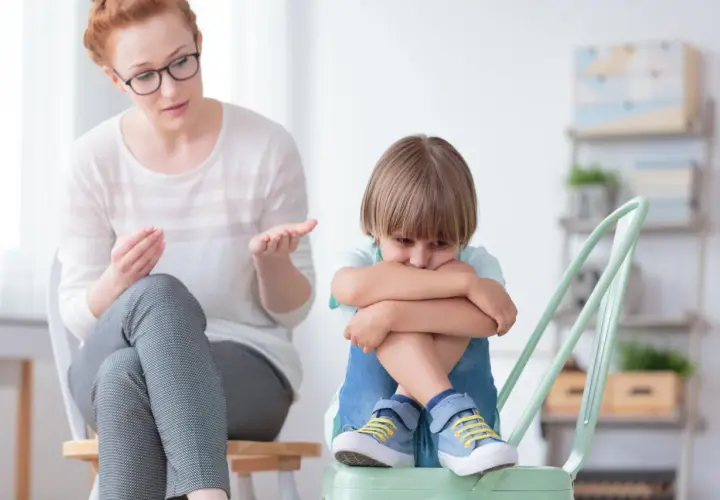 Nauczycielka wspomagająca rozmawia z chłopcem, który wygląda na smutnego. Jej pensum obejmuje wsparcie dzieci w trudnych chwilach.