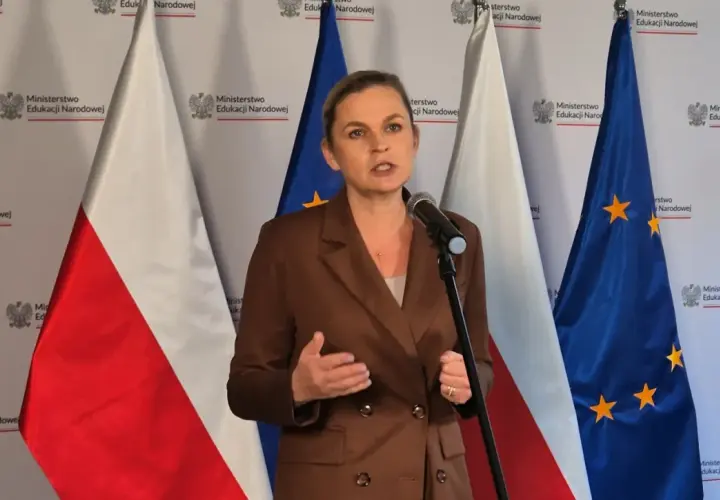 Ministerka przemawia o edukacji seksualnej w szkołach, stojąc przed flagami Polski i UE.
