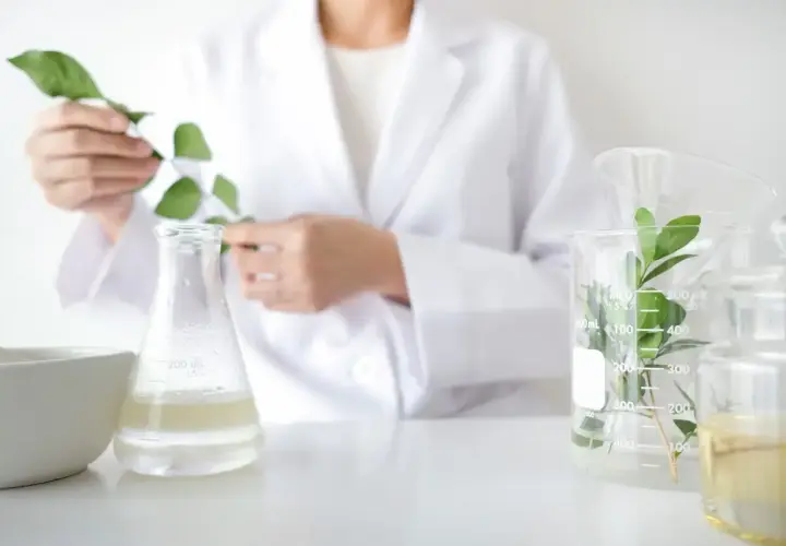 Biolog w białym fartuchu bada rośliny w laboratorium. Zastanawiasz się, ile zarabia biolog?