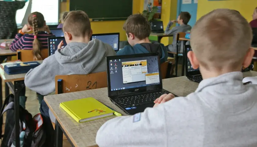 Dzieci w szkole pracują na laptopach. Nauczycielka tłumaczy materiał. Ile czasu ma nauczyciel na sprawdzenie sprawdzianu?