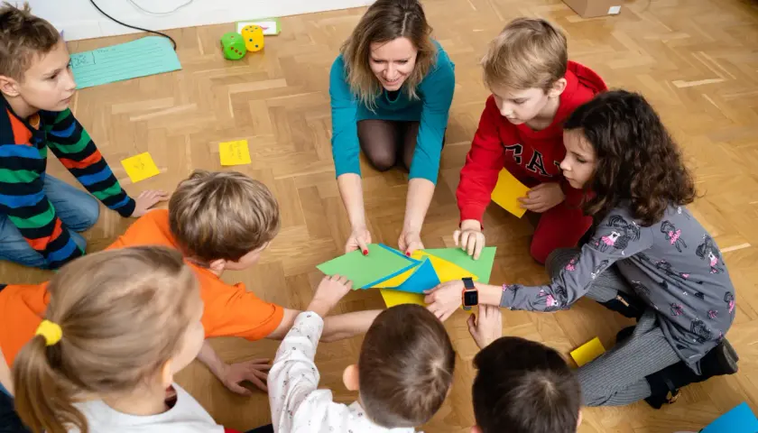 Nauczycielka przedszkola z dziećmi tworzy kolorową mozaikę. Każdy element to mały sukces, ale czasem coś nie pasuje, jak w życiu.