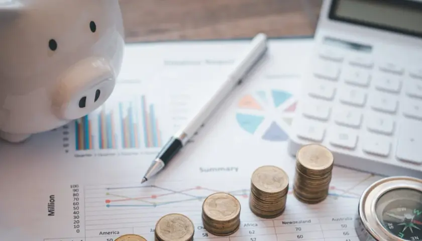 Świnka-skarbonka, monety, kalkulator i kompas na wykresach. Planowanie przyszłości po studiach finanse i rachunkowość.