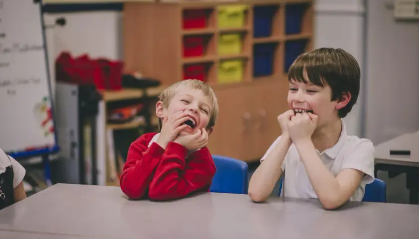 Dwóch chłopców śmieje się wesoło w klasie. Ich oceny z zachowania w szkole z pewnością będą wysokie!