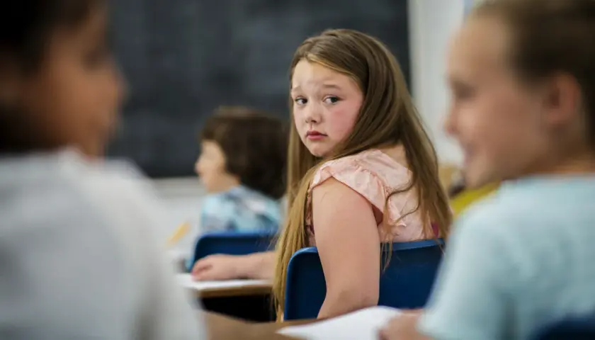 Smutna dziewczynka odwraca się, czując się samotna. W szkole dokuczanie może sprawić, że poczujesz się niewidzialny.