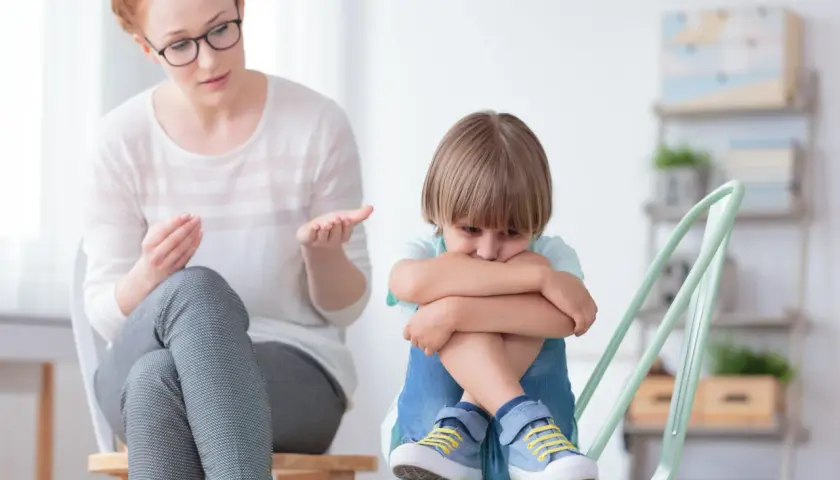 Nauczycielka wspomagająca rozmawia z chłopcem, który wygląda na smutnego. Jej pensum obejmuje wsparcie dzieci w trudnych chwilach.