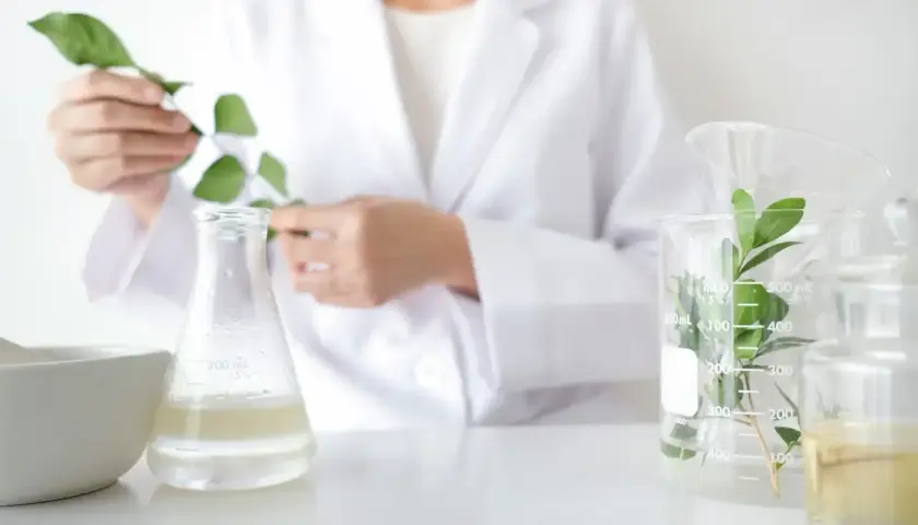 Biolog w białym fartuchu bada rośliny w laboratorium. Zastanawiasz się, ile zarabia biolog?