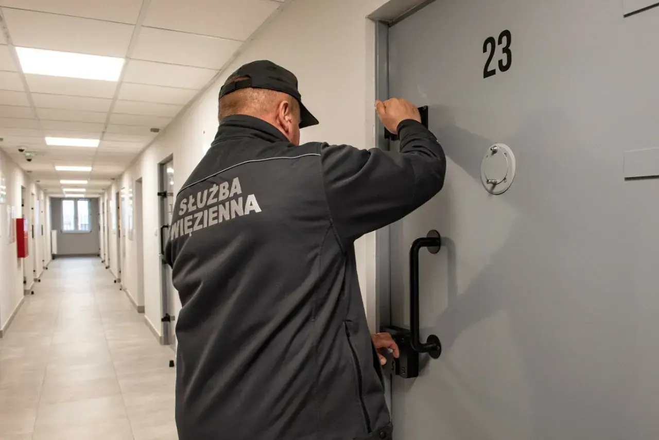 Wychowawca w więzieniu przy drzwiach celi nr 23. Zastanawiasz się, ile zarabia wychowawca w więzieniu?