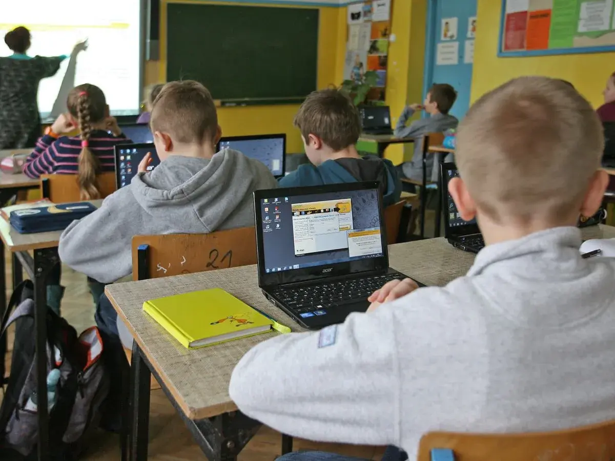 Dzieci w szkole pracują na laptopach. Nauczycielka tłumaczy materiał. Ile czasu ma nauczyciel na sprawdzenie sprawdzianu?