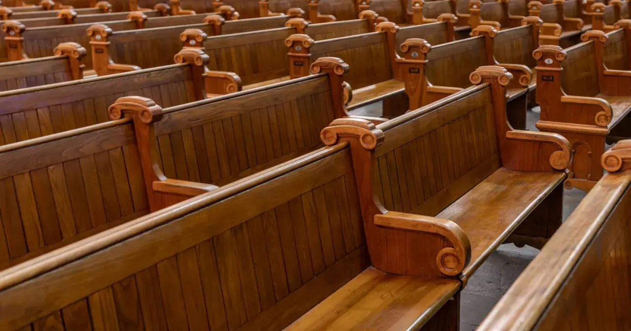 Puste, drewniane ławki w kościele, symbolizujące rezygnację z religii i pustkę po odejściu wiary.
