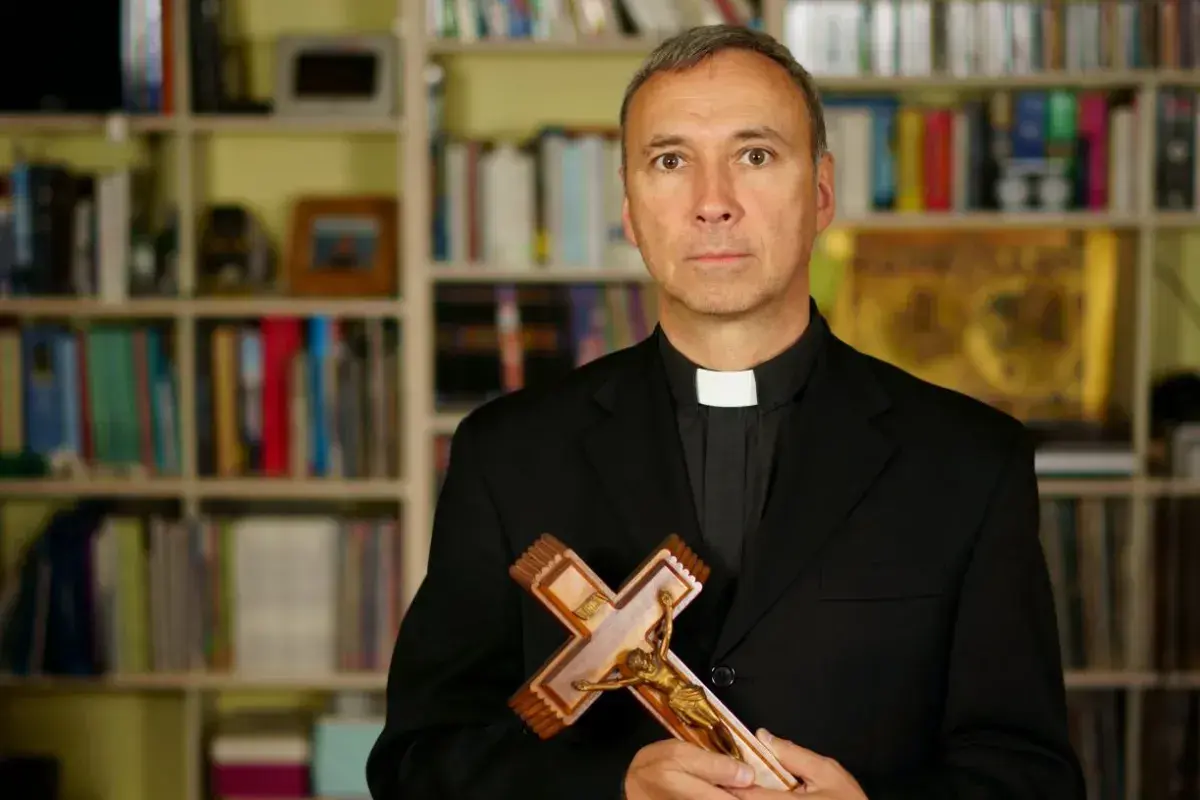 Duchowny z krzyżem w dłoniach, na tle regałów z książkami. Zastanawia się, od kiedy religia wlicza się do średniej.