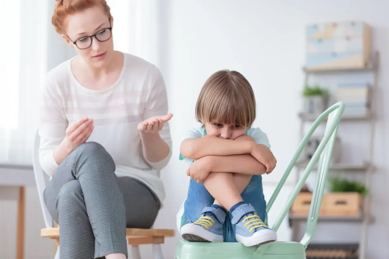Nauczycielka wspomagająca rozmawia z chłopcem, który wygląda na smutnego. Jej pensum obejmuje wsparcie dzieci w trudnych chwilach.