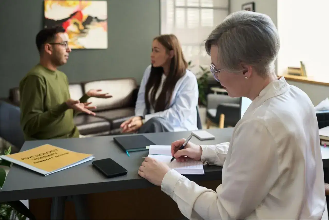 Terapia grupowa jako jedna z opcji po studiach psychologicznych. Terapeuta notuje, pacjenci rozmawiają.