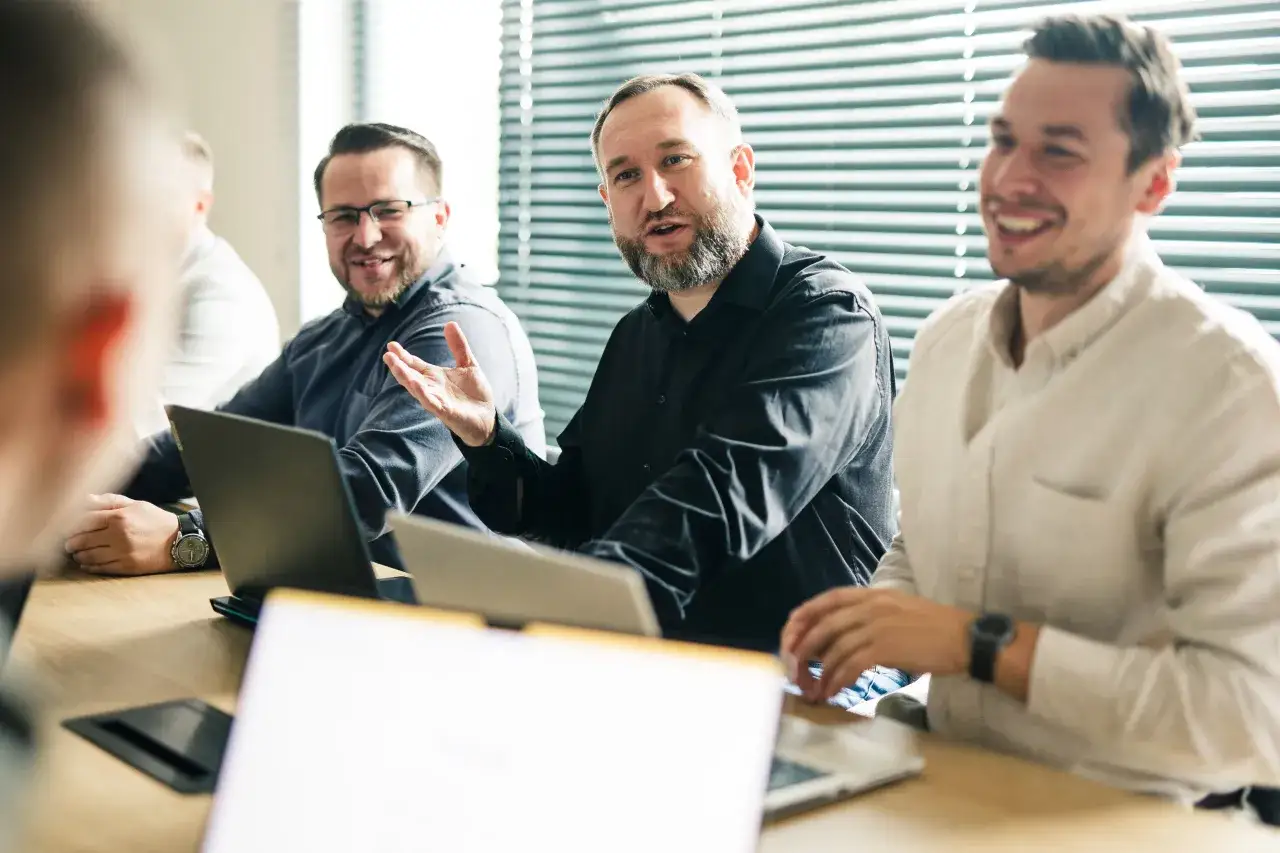 Mężczyźni dyskutują przy stole, omawiając możliwości kariery po studiach marketing i zarządzanie.