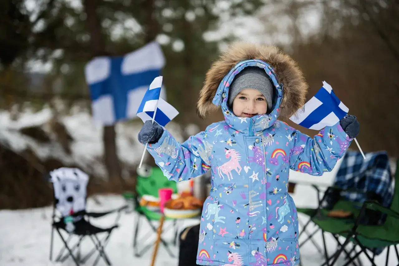 Dziecko z flagami Finlandii, symbol wolności i otwartości, jak system edukacji w Finlandii.