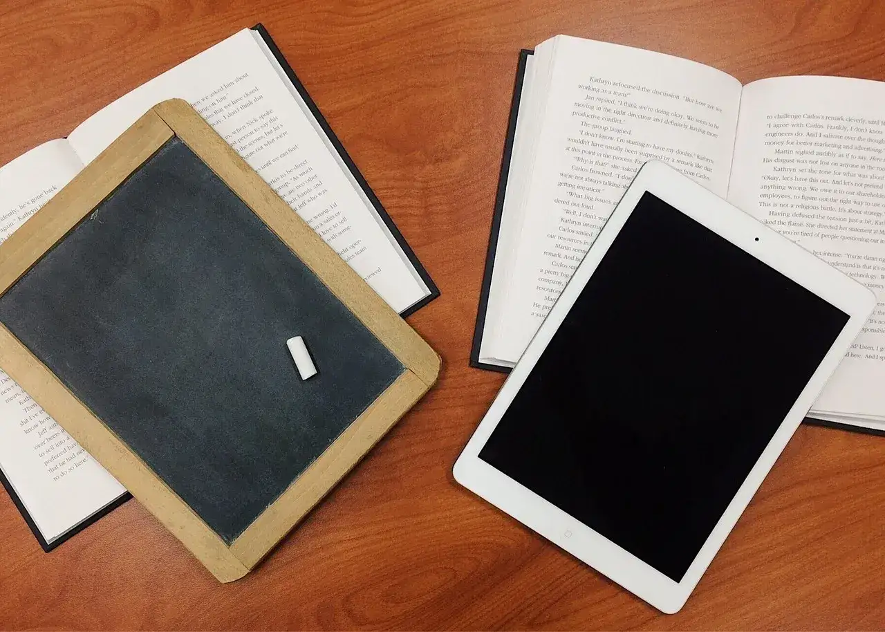 Tablica, kreda, książki i tablet symbolizują nowoczesne podejście do nauczania, jak w systemie edukacji w Finlandii.