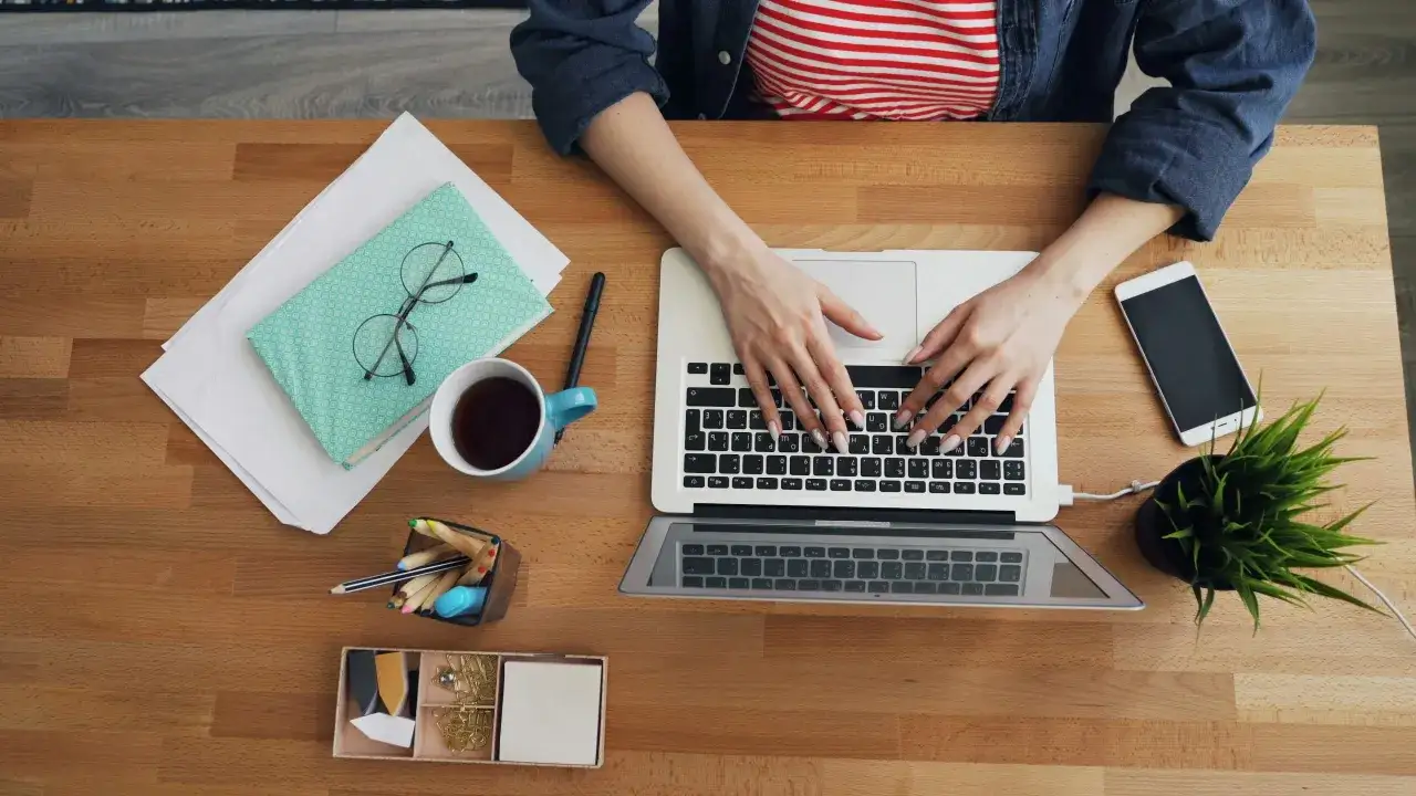 Praca przy laptopie, filiżanka kawy, notatnik i telefon – to wszystko może być częścią kariery po studiach marketing i zarządzanie.