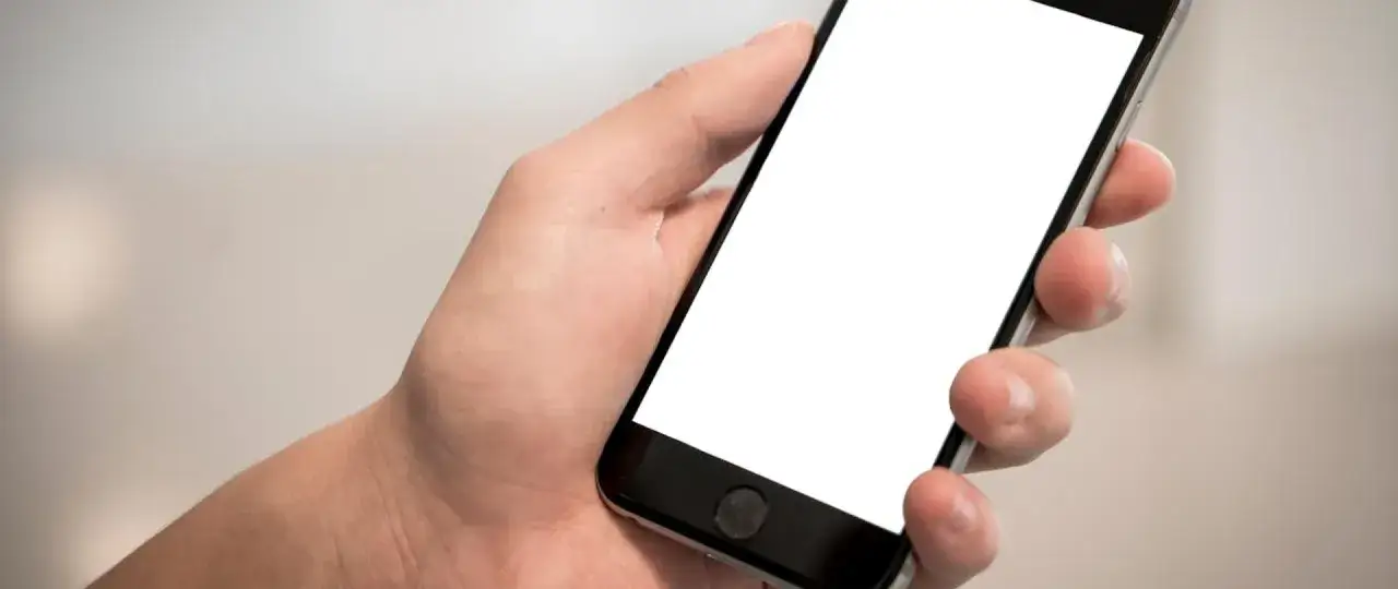 Dłoń trzyma smartfon z pustym ekranem. Czy nauczyciel może zabrać telefon?