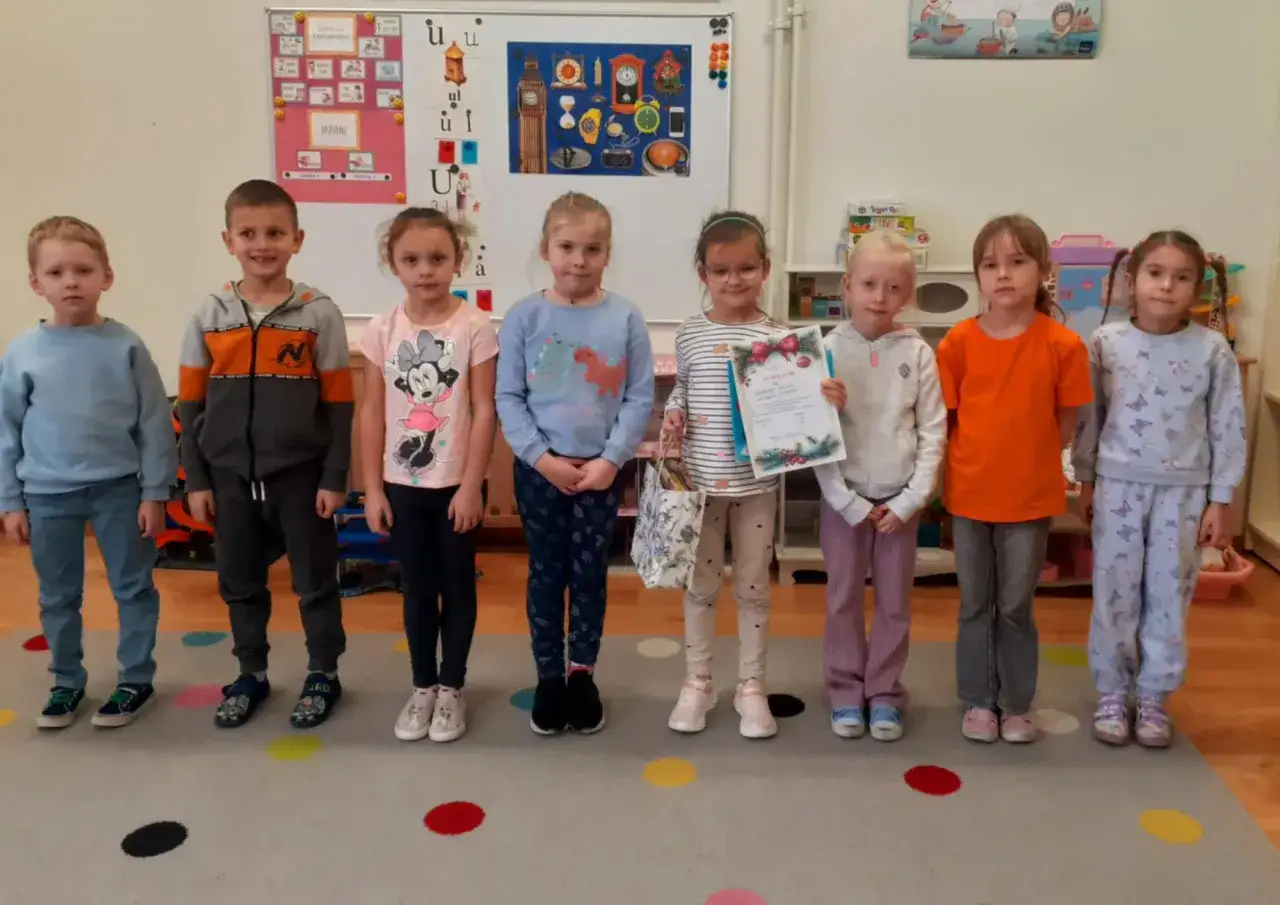 Dzieci w przedszkolu, jedna dziewczynka z dyplomem. Nauczycielka przedszkola świętuje sukcesy i porażki w pracy.